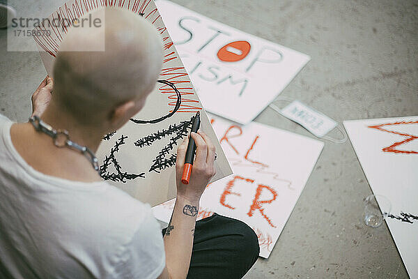Rückansicht einer glatzköpfigen Aktivistin  die ein Schild für eine soziale Bewegung vorbereitet