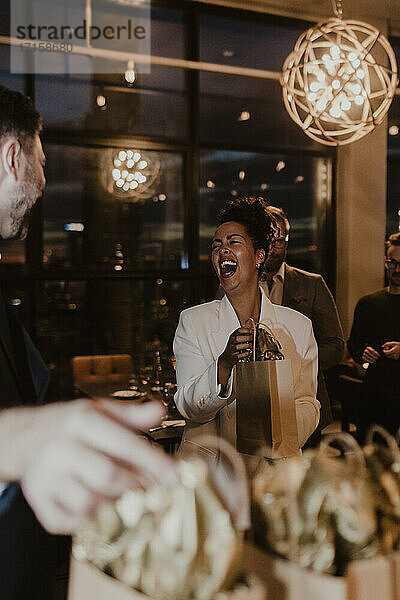 Fröhlich Geschäftsfrau lachen  während halten Geschenk Tasche im Büro Partei