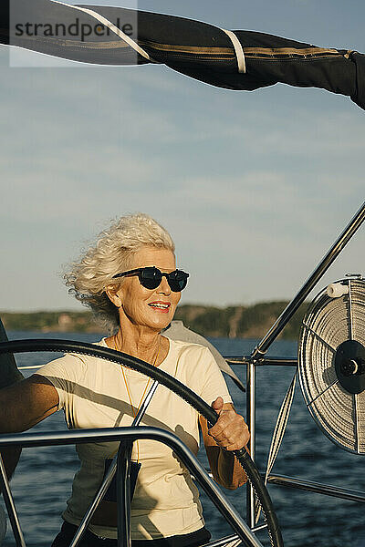 Lächelnde ältere Frau Segelboot im Meer an einem sonnigen Tag