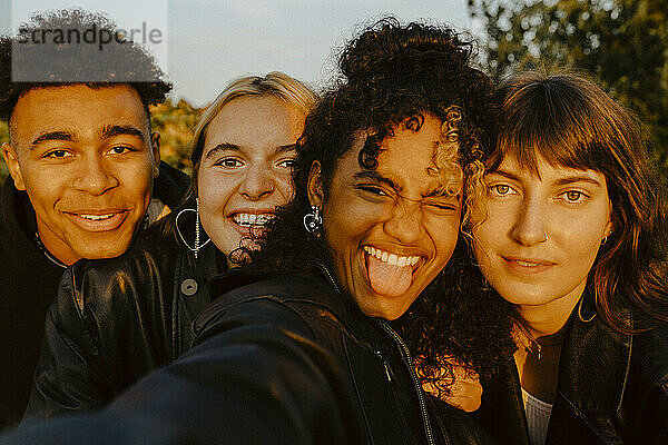 Fröhliche Freunde nehmen Selfie im Freien bei Sonnenuntergang