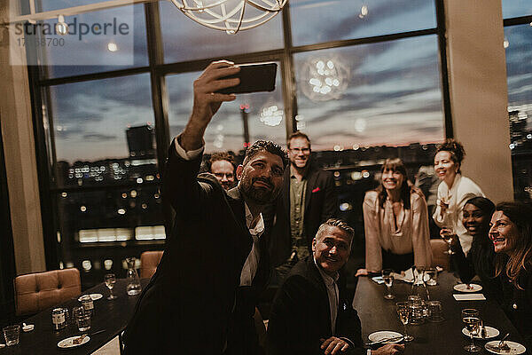 Lächelnde Geschäftsleute nehmen Selfie auf Handy im Büro während der Party