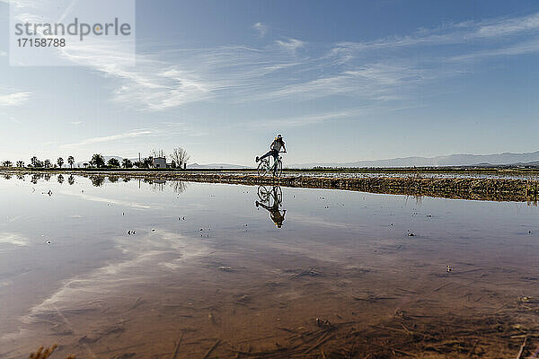 Fröhliche junge Frau auf dem Fahrrad an einem sonnigen Tag im Ebro-Delta  Spanien