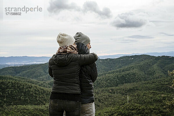 Touristisches Paar  das sich umarmt und wegschaut  während es an einem Aussichtspunkt steht