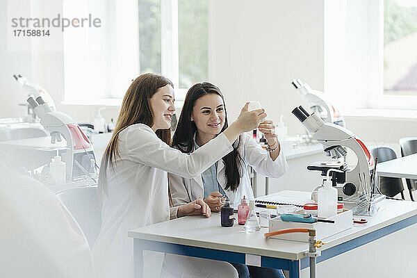 Junge Forscherinnen in weißen Kitteln bei der Analyse einer Laborprobe im Labor