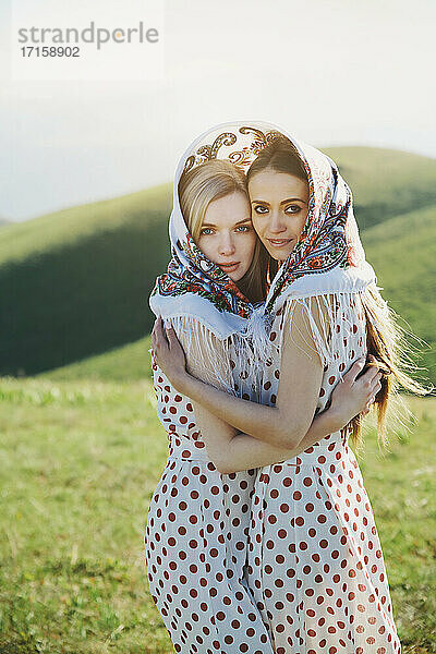 Lesbian couple with headscarf embracing each other while standing on meadow