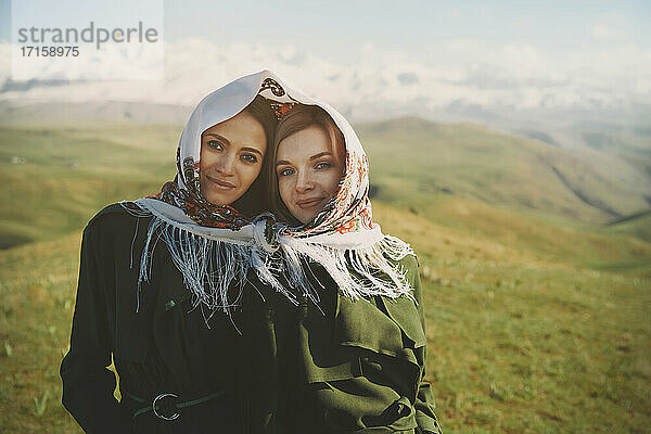 Smiling lesbian couple with headscarf at meadow