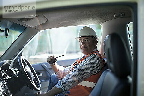 Male architect with walkie talkie sitting in truck at construction site