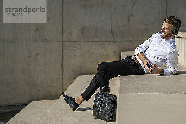 Businessman using mobile phone while relaxing on steps