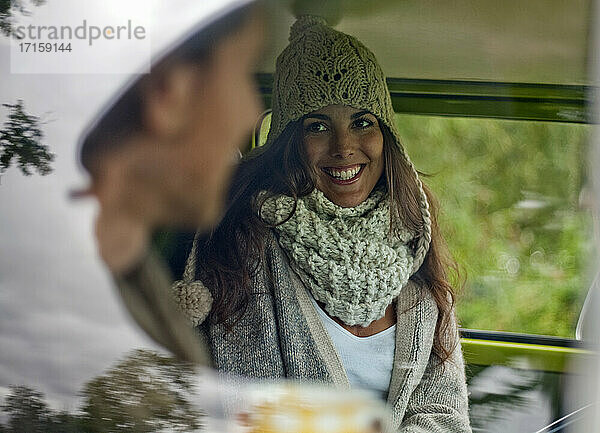 Beautiful woman smiling while talking with boyfriend in campervan