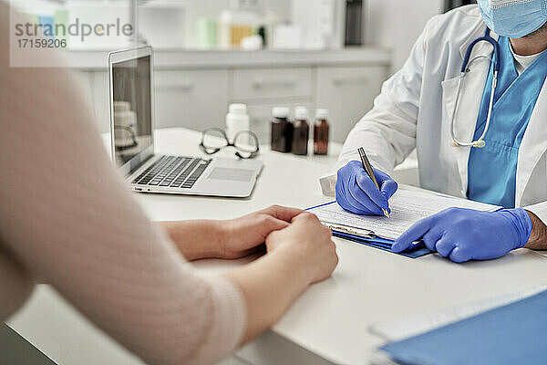 Medical professional writing treatments for patient in clinic
