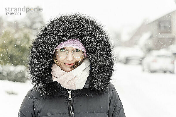 Woman in hooded anorak during snowfall