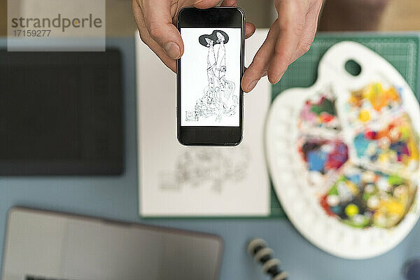 Künstlerin  die zu Hause mit ihrem Mobiltelefon ein Designfoto aufnimmt
