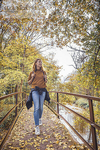 Mature woman walking on bridge in forest