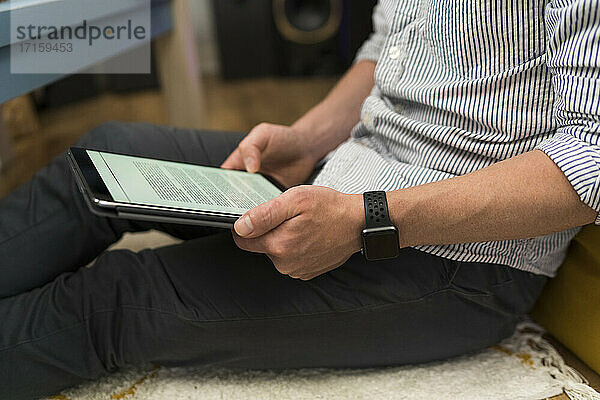 Geschäftsmann  der ein digitales Tablet benutzt  während er zu Hause sitzt