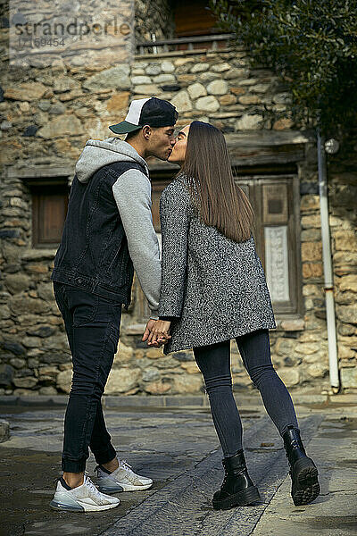 Romantisches junges Paar hält sich an den Händen und küsst sich auf der Straße