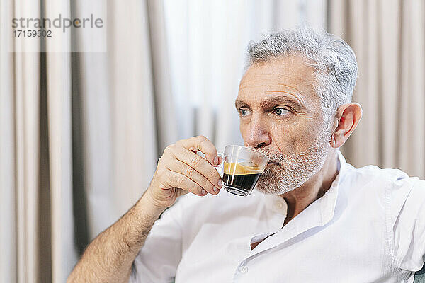 Contemplating man drinking coffee in hotel room