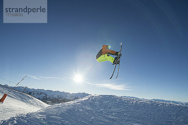Male skier jumping against sky