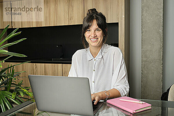 Porträt einer jungen Frau  die zu Hause am Laptop arbeitet