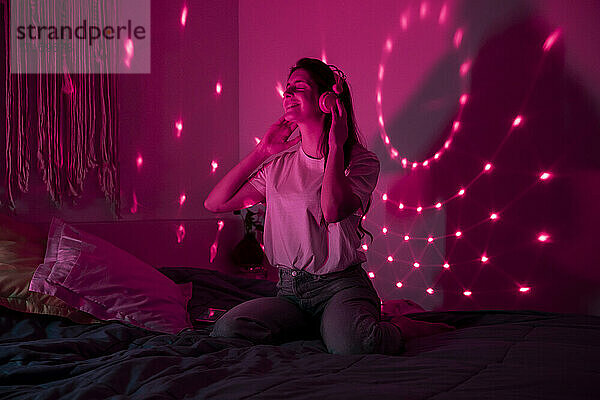 Young woman enjoying music in bedroom at home