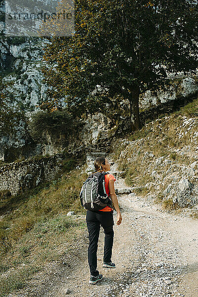 Hiker wearing backpack looking away while walking on Cares Trail at Picos De Europe National Park  Asturias  Spain
