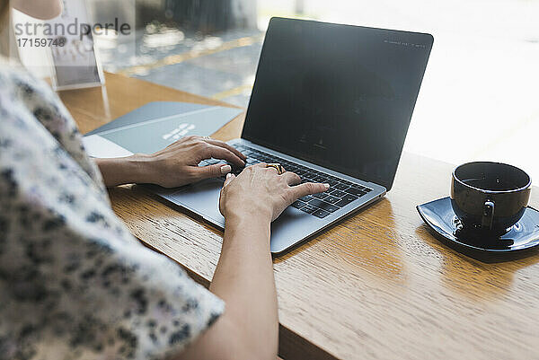 Hände einer Geschäftsfrau bei der Arbeit am Laptop in einem Café