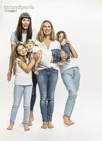 Happy mothers and siblings carrying sister against white background in studio