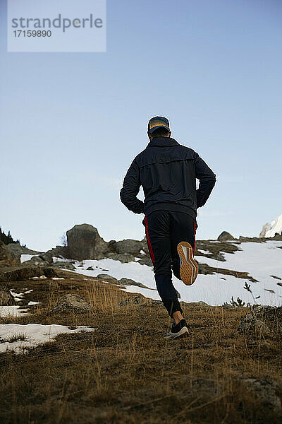 Junger männlicher Sportler beim Joggen auf einem Berg im Winter