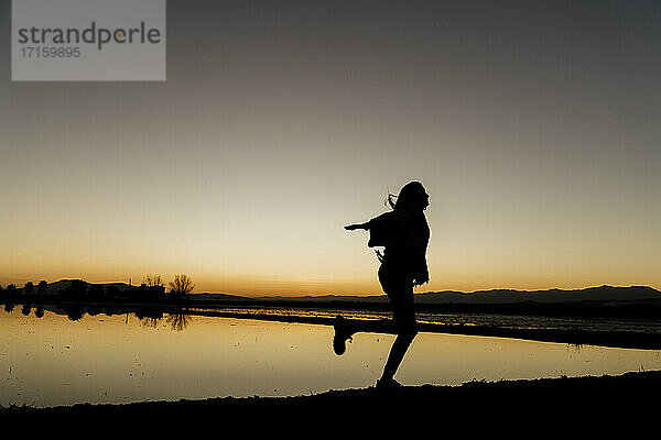 Junge Frau  die sich bei Sonnenuntergang im Ebro-Delta  Spanien  auf einem Bein dreht