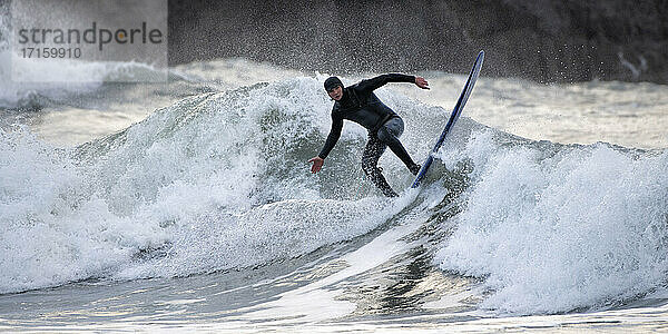 Männlicher Surfer surft auf Wellen  die im Meer plätschern  Broad Haven South Beach  Wales  UK