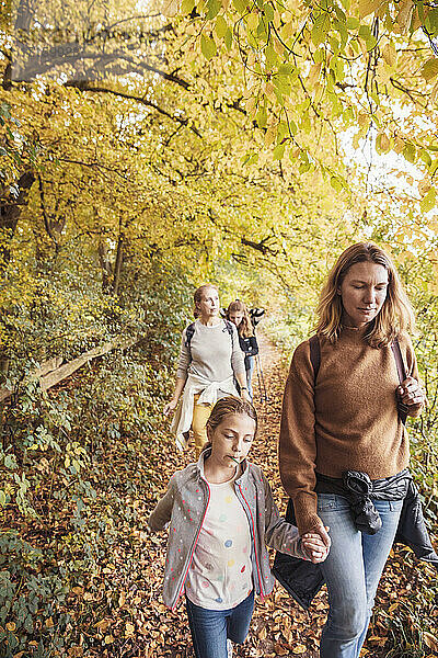 Mature women walking with children while hiking in forest