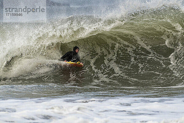 Ältere männliche Sportlerin beim Bodyboarding auf den Wellen im Meer bei Broad Haven South  UK