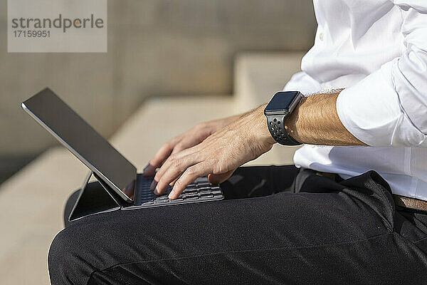 Businessman using digital tablet while sitting outdoors