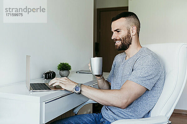 Lächelnder Mann arbeitet zu Hause am Laptop