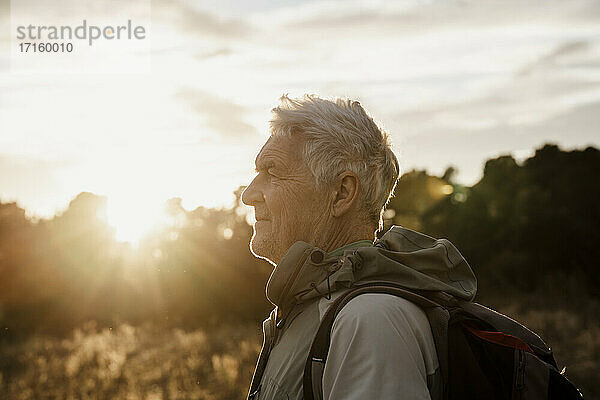 Älterer Mann in warmer Kleidung mit Blick auf den Sonnenuntergang