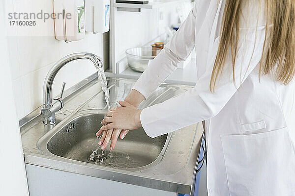 Crop-Ansicht einer Wissenschaftlerin beim Händewaschen im Labor