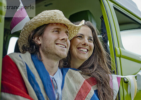 Smiling woman with boyfriend in camper van looking away