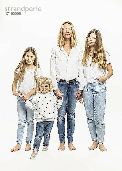 Mother and daughters holding hands while standing in studio
