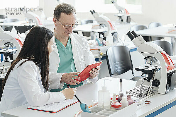 Wissenschaftler in weißen Kitteln verwenden Tablette im Labor
