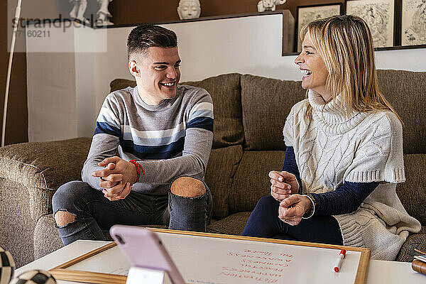 Weiblicher Berater und junger Mann lachen während einer Motivationssitzung am Arbeitsplatz