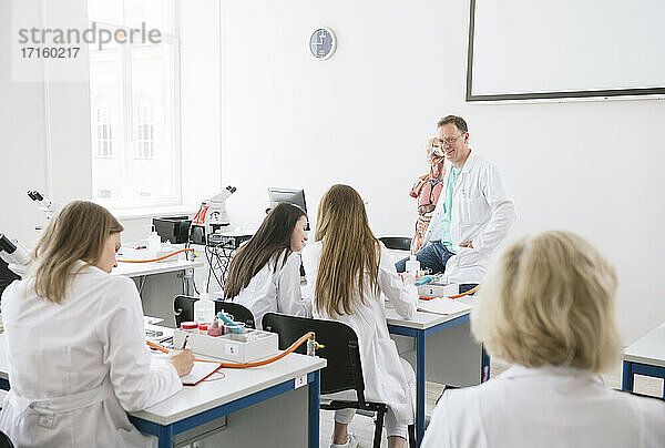 Studenten halten eine Vorlesung mit einem Professor in einem wissenschaftlichen Labor