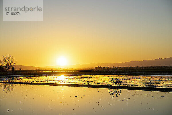 Spiegelung eines Fahrrads im Ebro-Delta bei Sonnenuntergang  Spanien