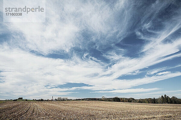 Barren agricultural field against blue sky at countryside