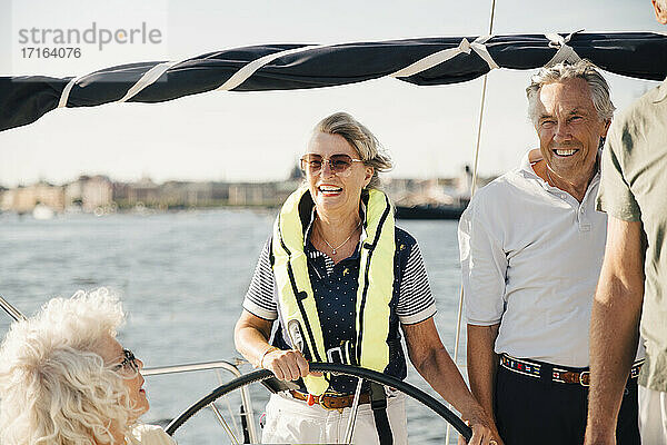 Fröhliche ältere Frau Segelboot mit glücklichen Freunden auf sonnigen Tag