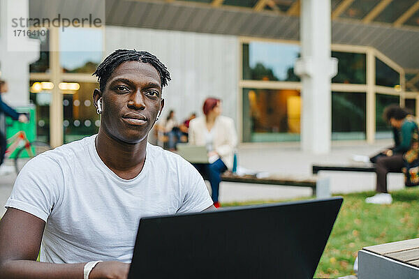 Porträt eines afrikanischen männlichen Studenten mit Laptop in der Universität