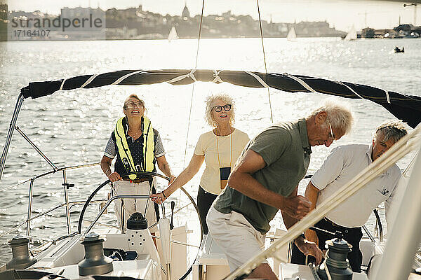 Senior männliche und weibliche Freunde Segelboot auf sonnigen Tag im Meer