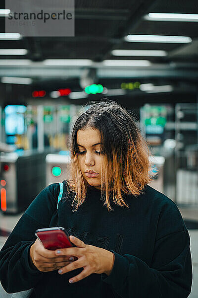 Weibliche Studentin benutzt Smartphone in der U-Bahn während der Nacht