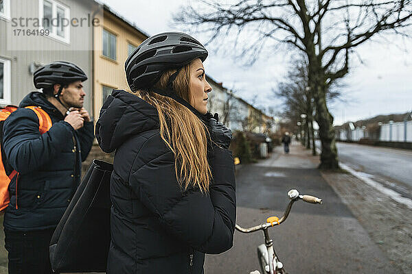 Heterosexuelles Paar mit Fahrradhelm auf dem Gehweg in der Stadt