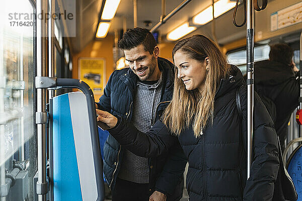 Lächelndes Paar kauft Fahrkarte beim Pendeln durch Straßenbahn