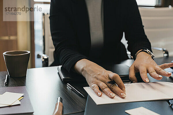 Mittelteil der Geschäftsfrau mit Stift und Tagebuch am Schreibtisch im Büro