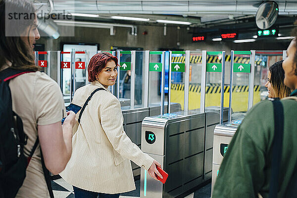 Porträt einer jungen Studentin  die in einer U-Bahn-Station über die Schulter schaut